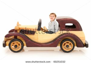 three year old-boy-sitting-in-wooden-toy-car-over-white-background-with-60251032